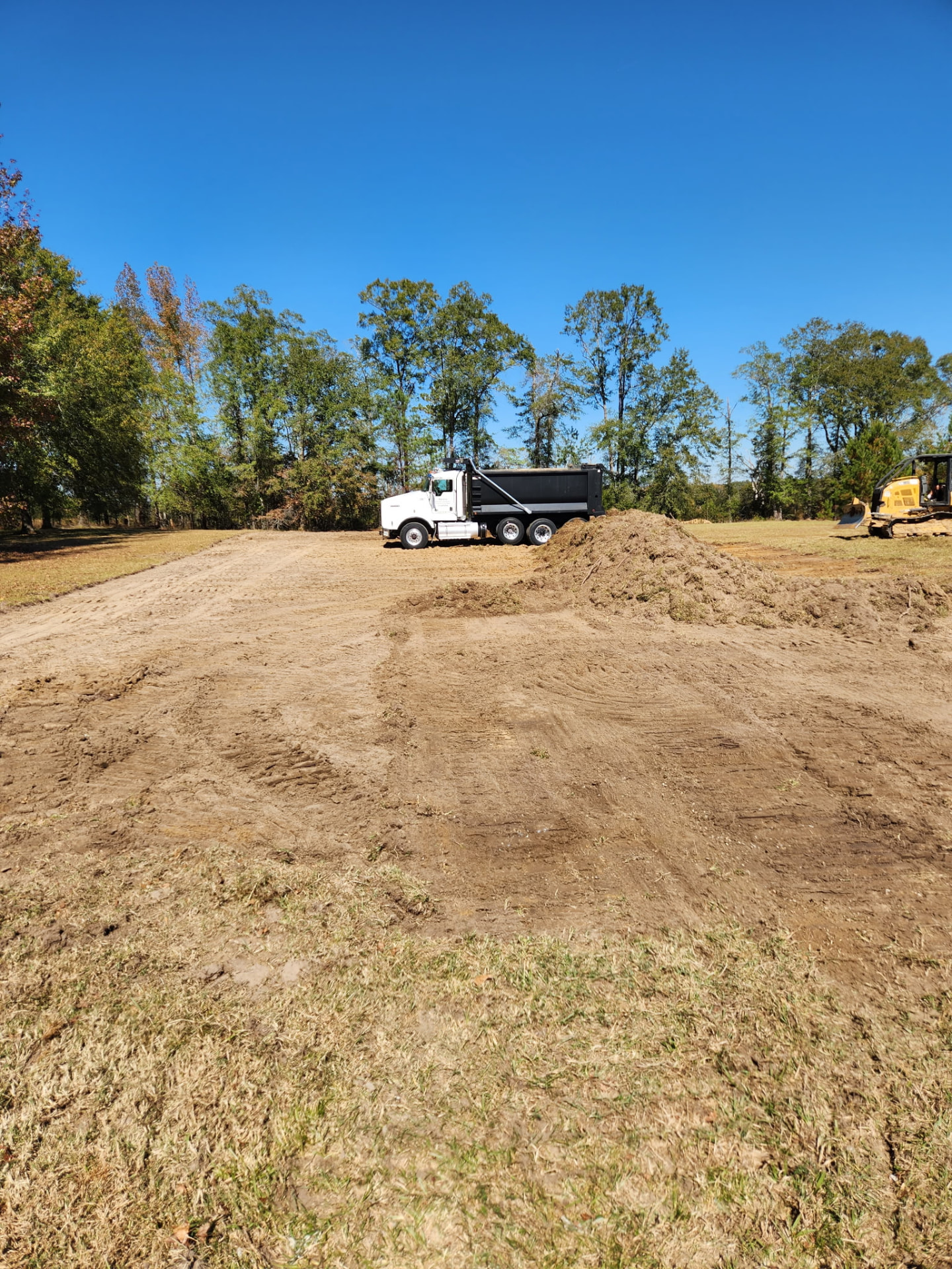 Bravo Fence land clearing crew with dump truck and dozer clearing an Alabama job site