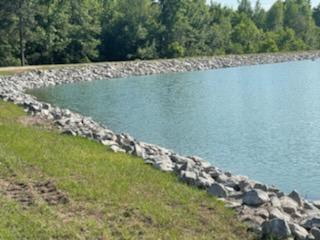 Rip rap rock shoreline stabilization along an Alabama pond by Bravo Fence and Construction